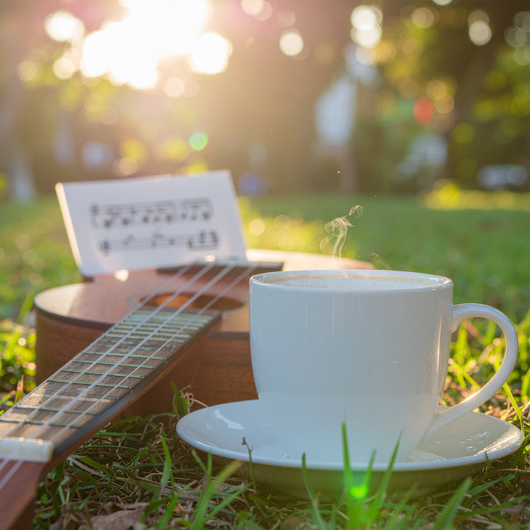 Light-colored coffee cup in morning sunlight, guitar in background