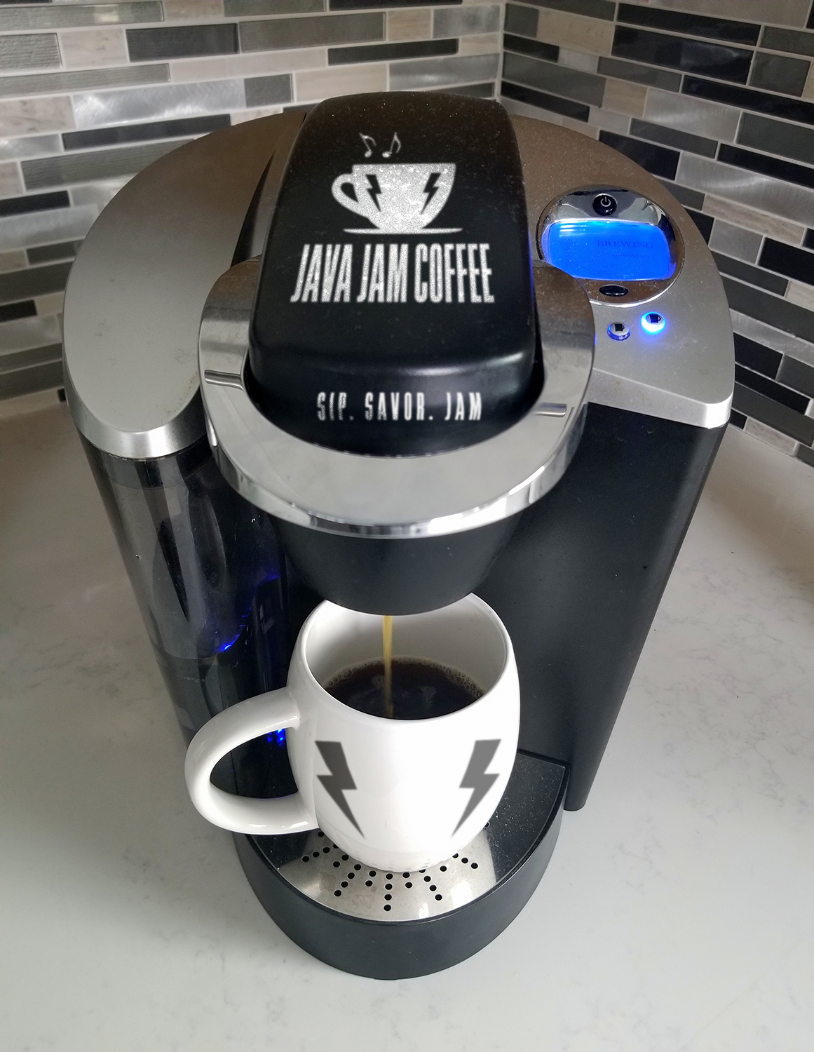 Coffee machine labeled 'Java Jam Coffee' dispensing coffee into a white mug with a black logo.