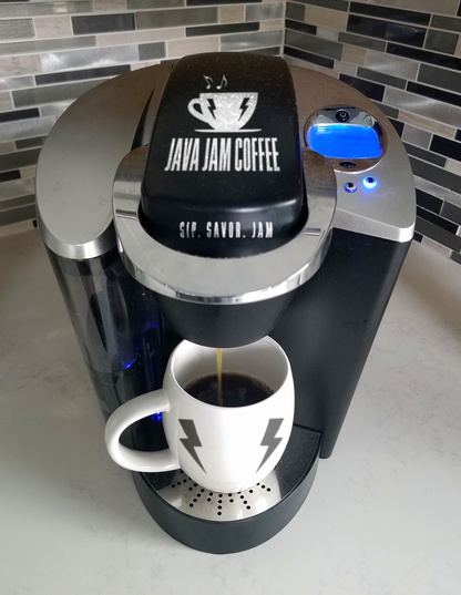 Coffee machine labeled 'Java Jam Coffee' dispensing coffee into a white mug with a black logo.